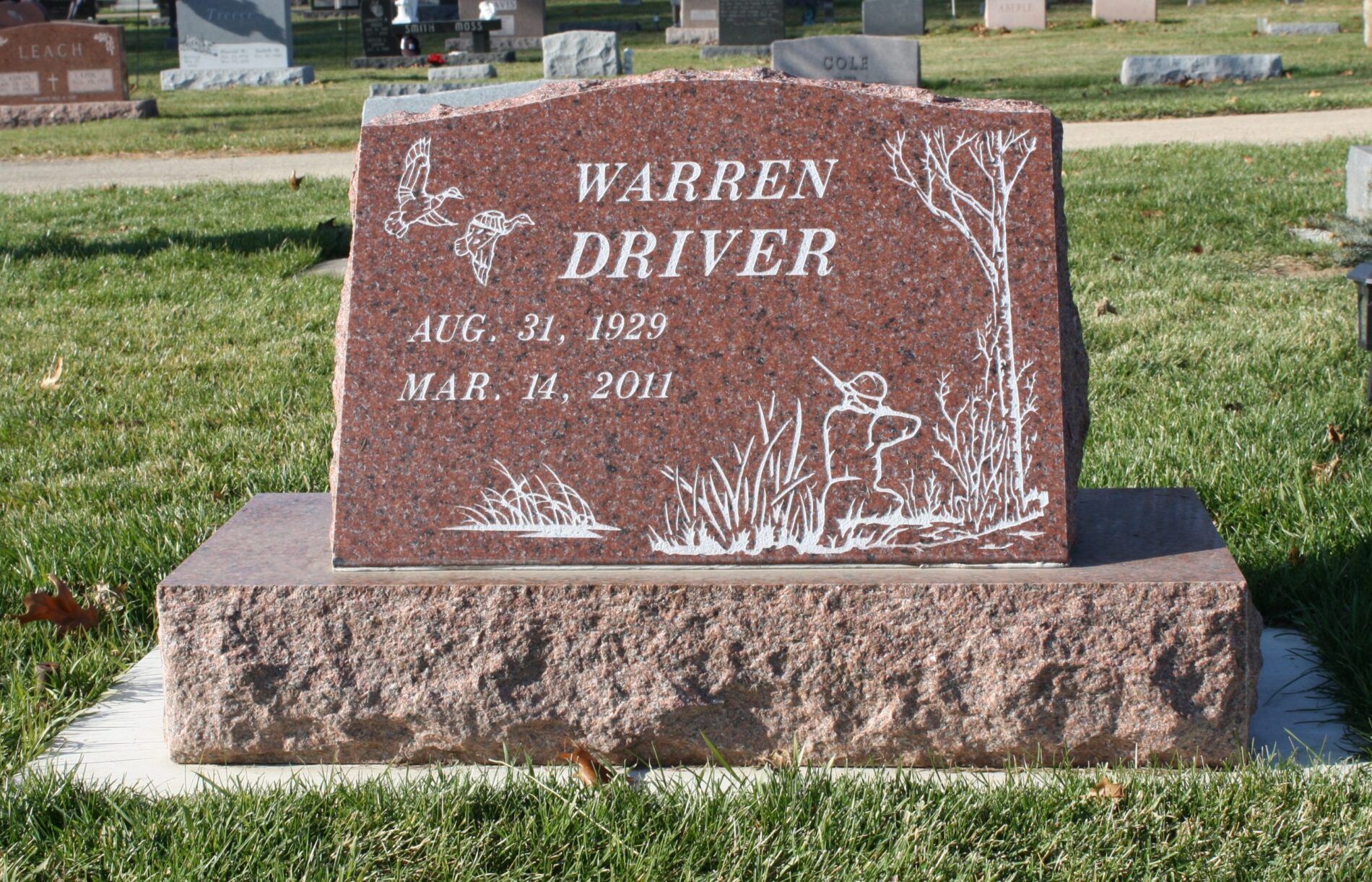 A gravestone for Warren Driver, showing dates August 31, 1929 to March 14, 2011, with hunting scene engravings.