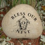 Granite memorial stone engraved with “Bless Our Nest” and decorative birds and nature design.