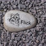 Gray granite upright headstone monument with polished finish in a peaceful cemetery setting.