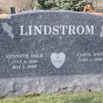 Gray granite double upright headstone monument for two graves in a cemetery memorial setting.