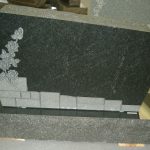 Polished double granite headstone monument with curved top for two graves in a cemetery.