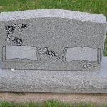 Double upright granite headstone monument for two graves in a cemetery memorial setting.